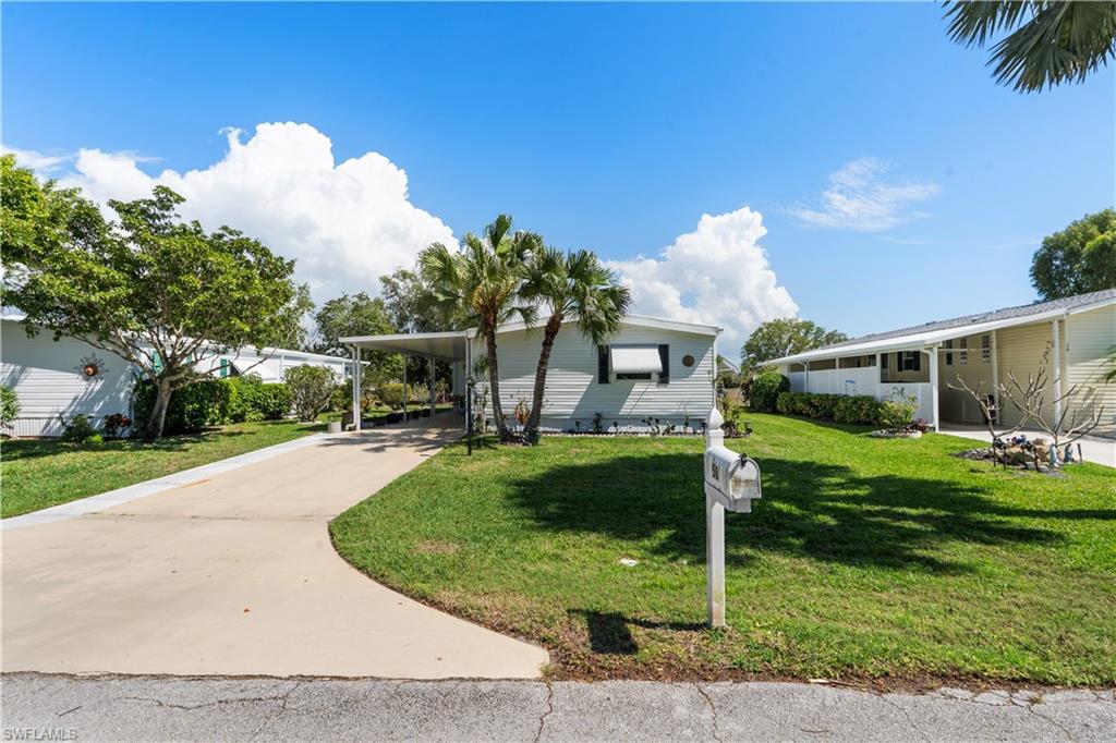 Single-story home featuring a carport, concrete driveway, and established landscaping