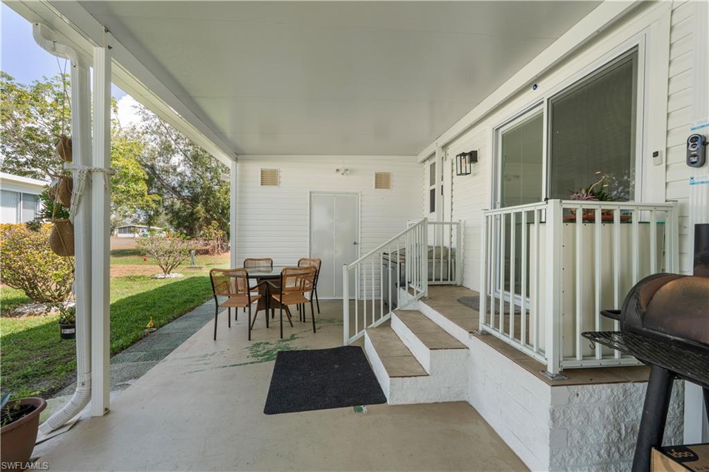 Covered outdoor patio area featuring a concrete slab, white siding, and a partial outdoor railing