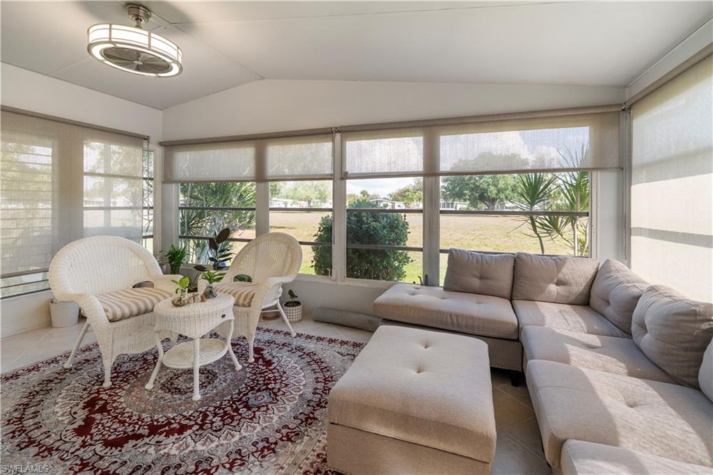 Enclosed sunroom featuring multiple large windows with roller shades, a flush-mount ceiling fan, and tile flooring