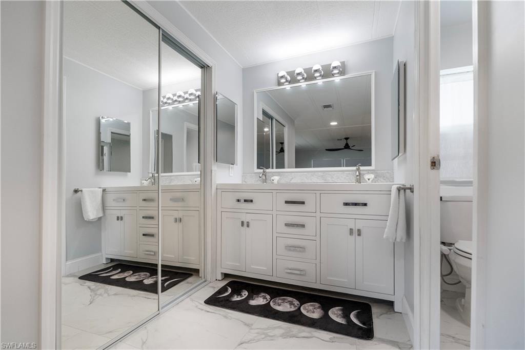 Bathroom featuring dual vanities with white cabinetry, light-toned countertops, and framed mirrors