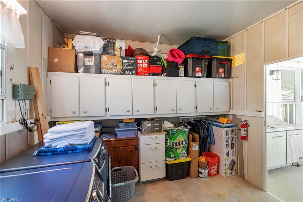 Utility room featuring extensive built-in cabinetry, durable wall paneling, and a clothes washer