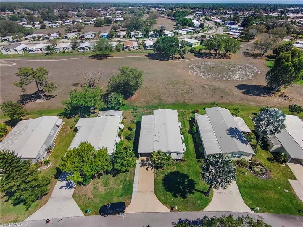 Aerial perspective of a neighborhood featuring multiple residences with light-colored roofing and manicured lawns