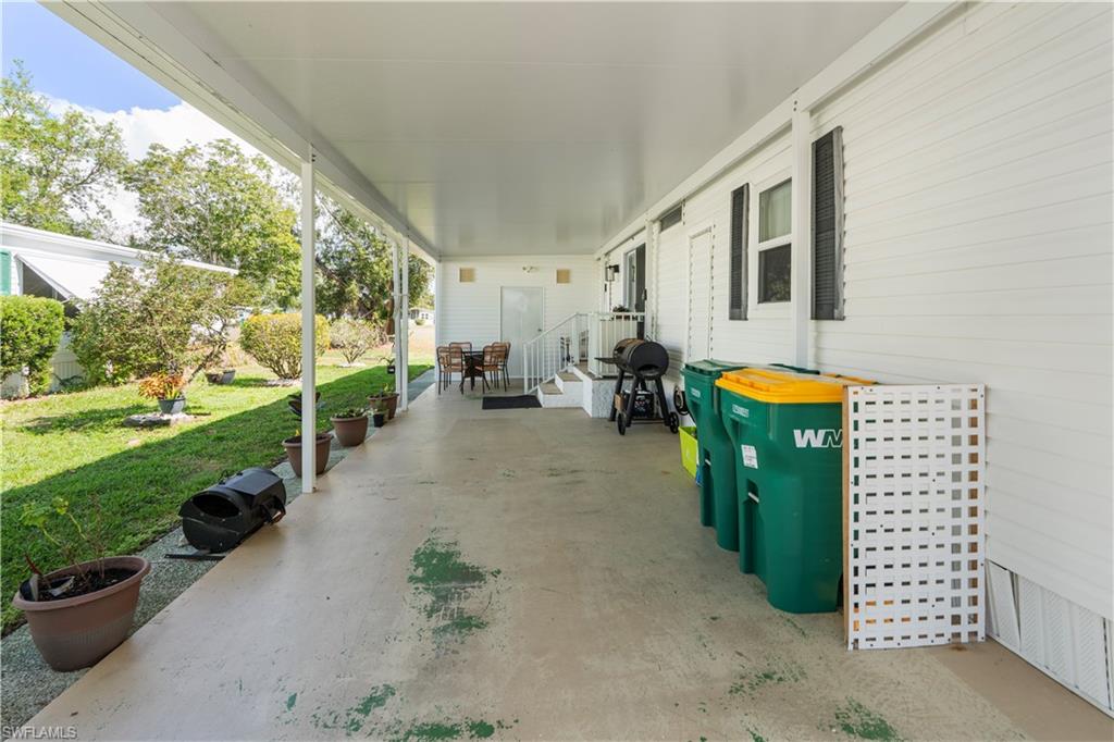 Covered patio with concrete flooring, white paneled siding, and a white railing