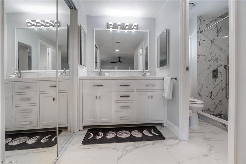 Double vanity featuring white cabinetry with silver hardware, white countertops, and dual mirrors with integrated lighting