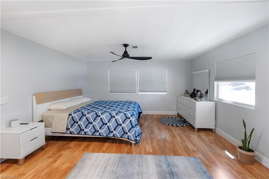 Spacious room featuring wood-finish flooring, light gray wall paint, and a white paneled ceiling