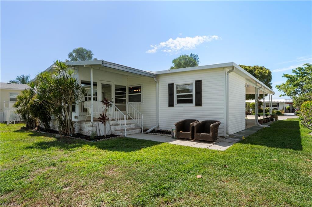 White siding exterior featuring a covered porch with railings, a paved patio area, and a covered carport
