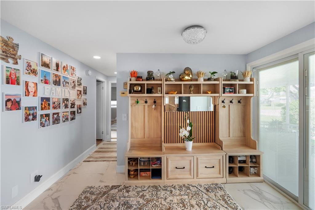 Entryway featuring wood-finish built-in storage, a sliding glass door, recessed lighting, and large format tile flooring