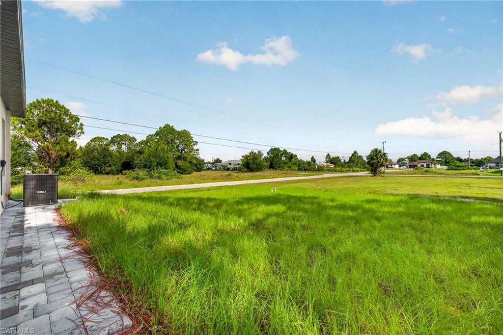 Extensive green space bordering a paver patio with a visible utility unit