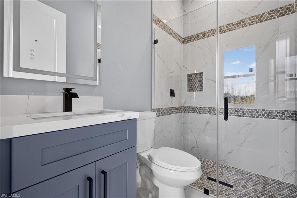 Contemporary bathroom featuring a floating vanity with a white countertop and integrated sink, a sleek black faucet, and an illuminated mirror