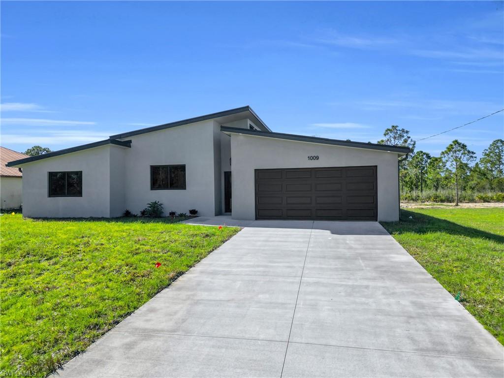 Contemporary house featuring a front lawn, stucco siding, concrete driveway, and a garage