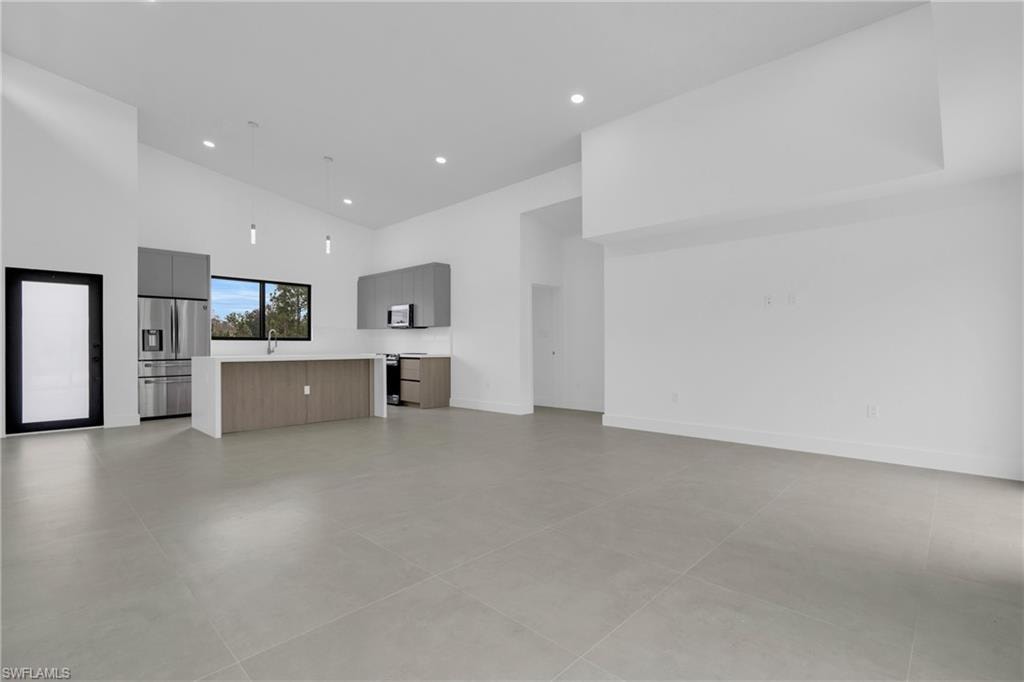 Unfurnished living room with high vaulted ceiling and recessed lighting
