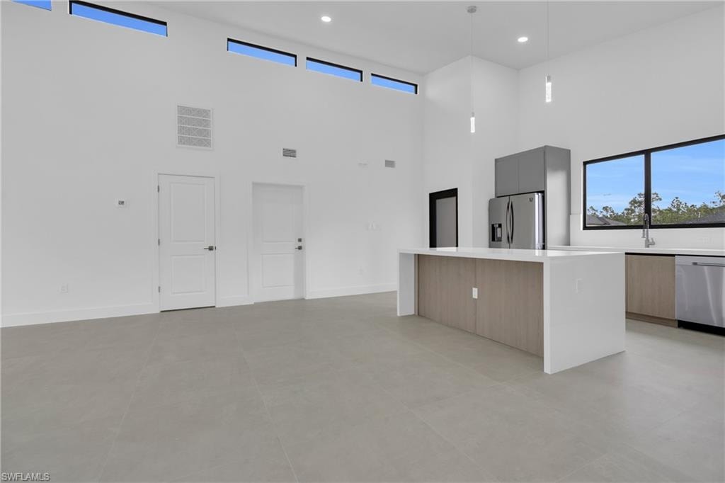 Kitchen with a center island, modern cabinets, appliances with stainless steel finishes, hanging light fixtures, and recessed lighting