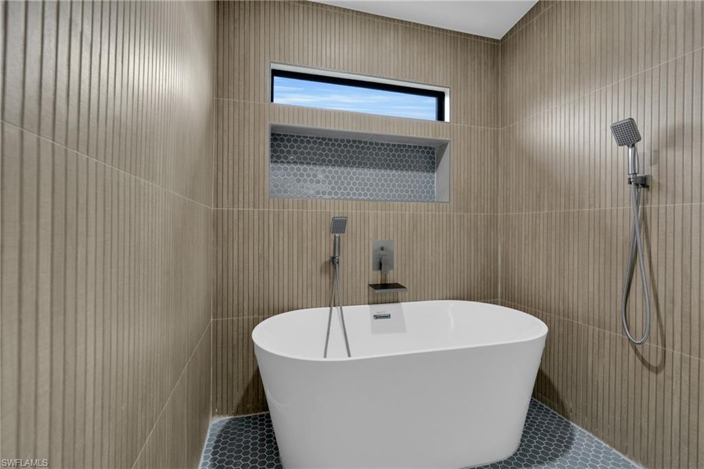 Full bath with a freestanding bath, tile walls, and tile patterned flooring