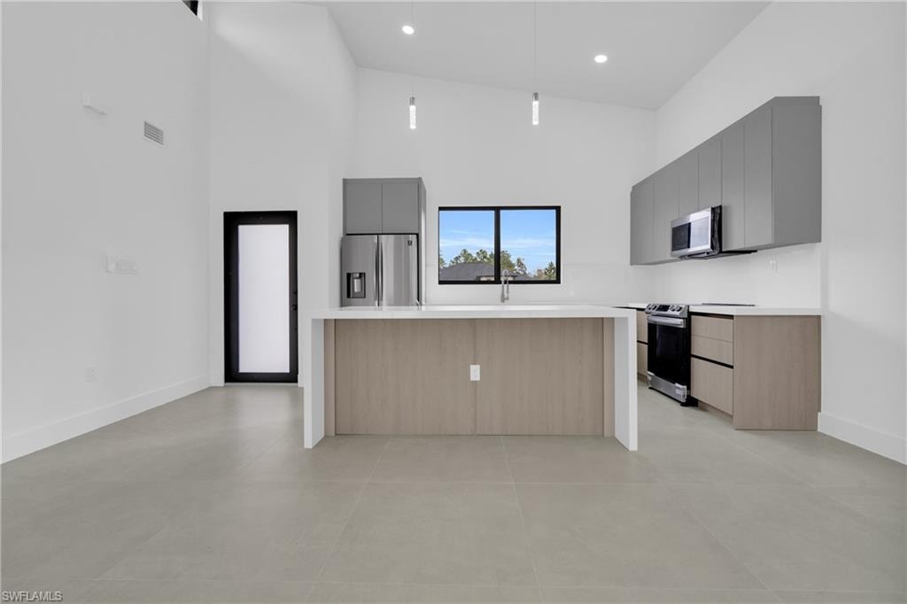 Kitchen featuring a kitchen island, modern cabinets, high vaulted ceiling, stainless steel appliances, and gray cabinetry
