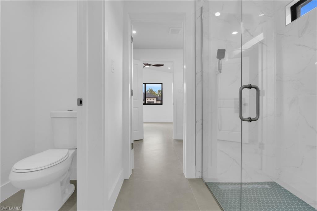 Bathroom featuring a marble finish shower, concrete flooring, recessed lighting, and ceiling fan