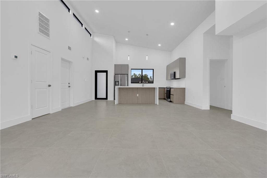 Unfurnished living room featuring a high ceiling and recessed lighting