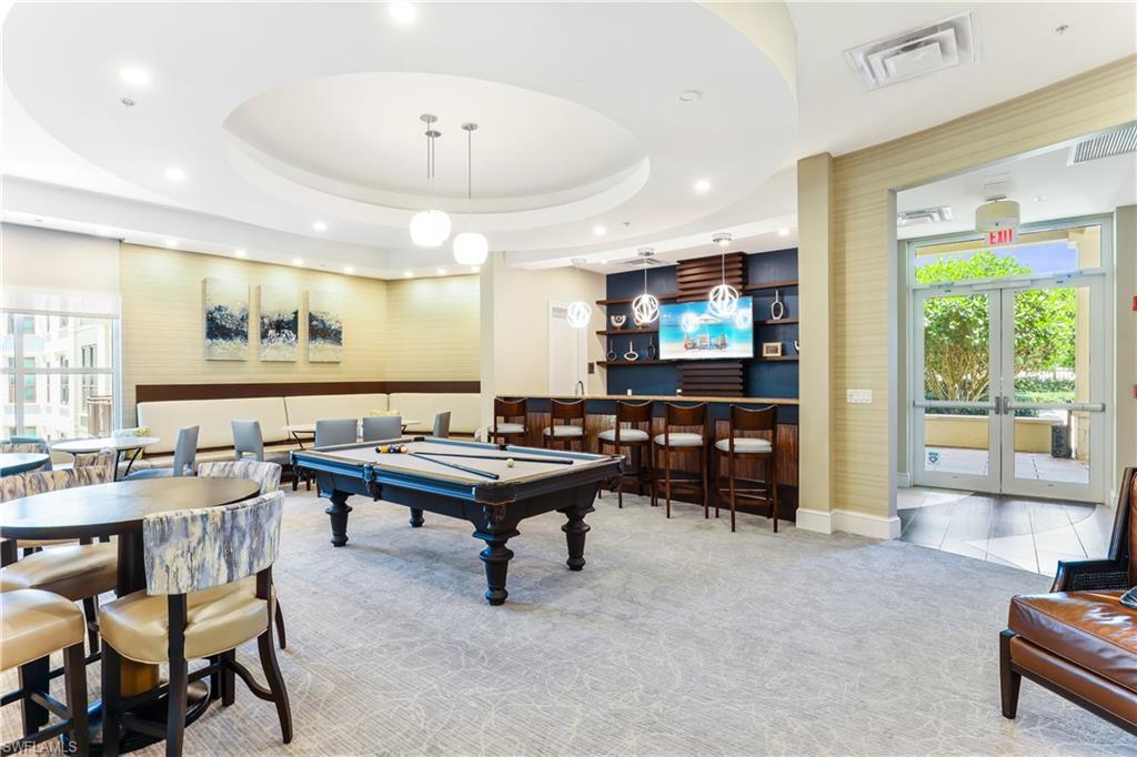Game room featuring pool table, french doors, light colored carpet, a tray ceiling, and bar