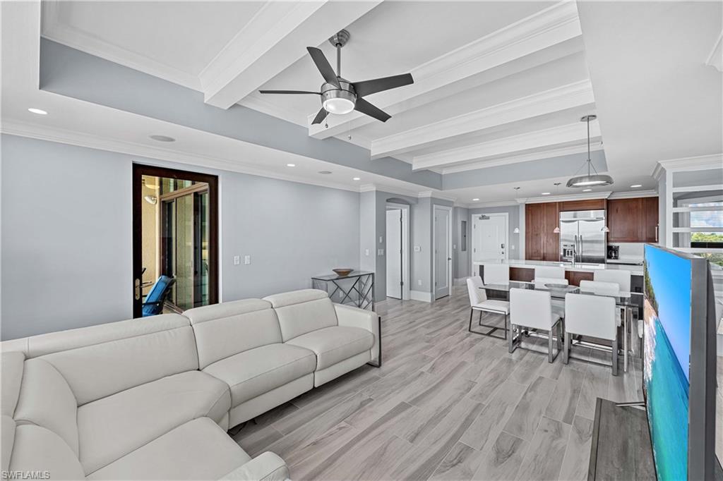 Living room with ceiling fan, beam ceiling, crown molding, and light hardwood / wood-style flooring