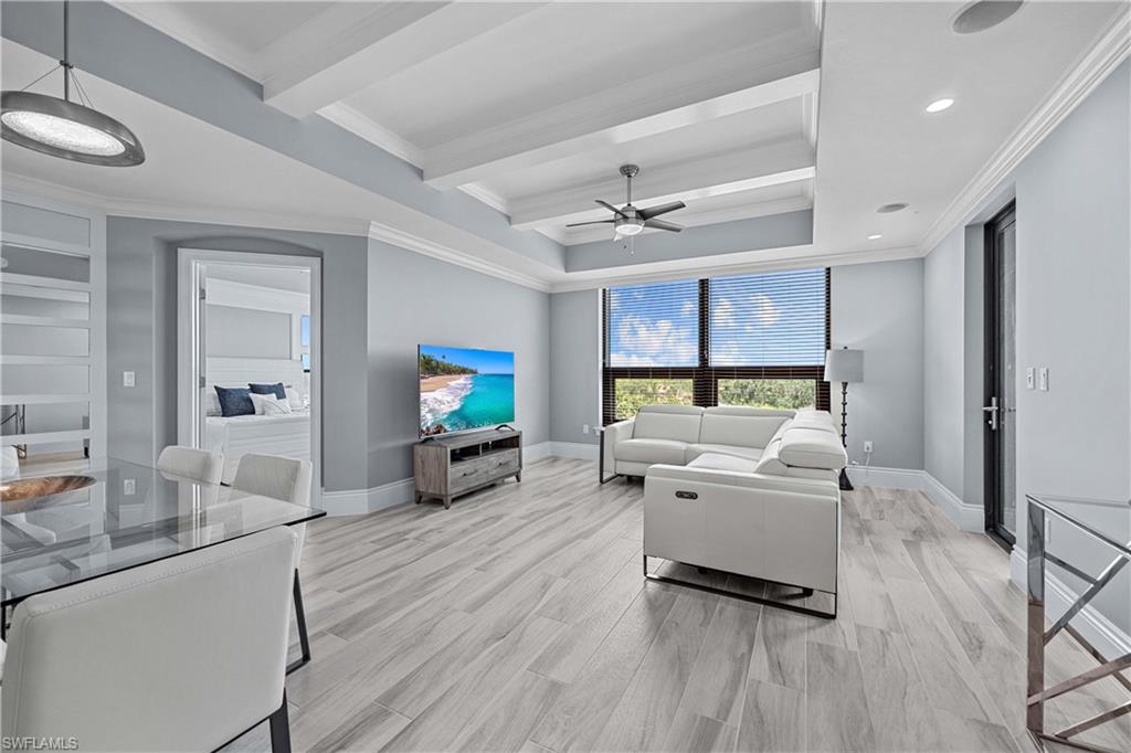 Living room with ceiling fan, light hardwood / wood-style floors, and ornamental molding