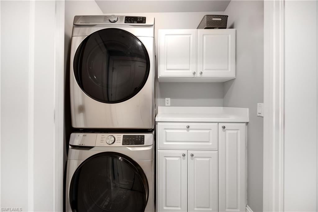 Clothes washing area with cabinets and stacked washer / dryer