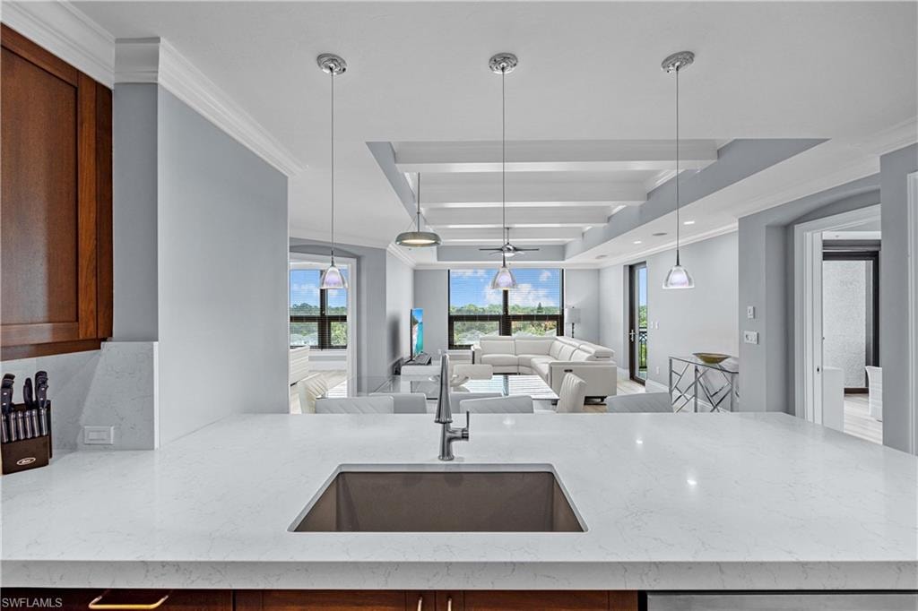 Kitchen featuring crown molding, pendant lighting, sink, and light stone countertops