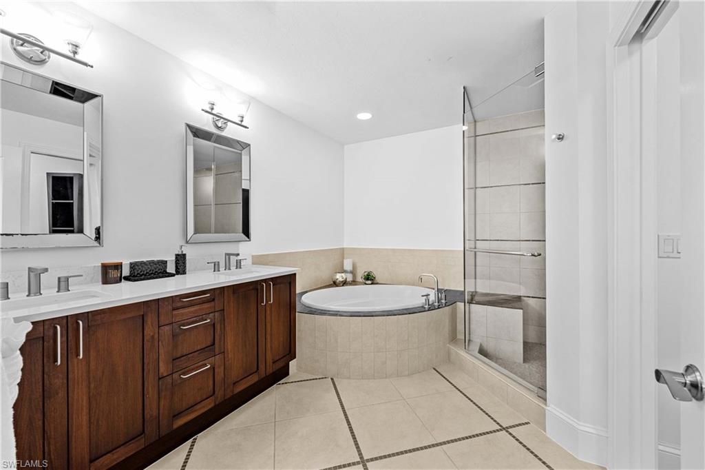 Bathroom with tile patterned flooring, independent shower and bath, and vanity