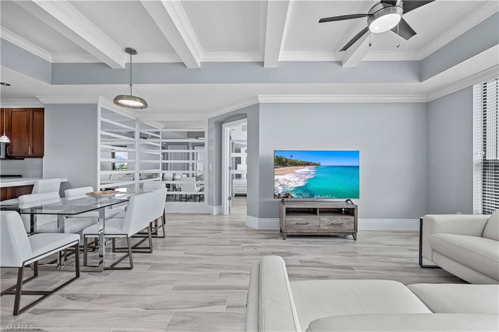 Living room with ceiling fan, ornamental molding, beamed ceiling, and light wood-type flooring
