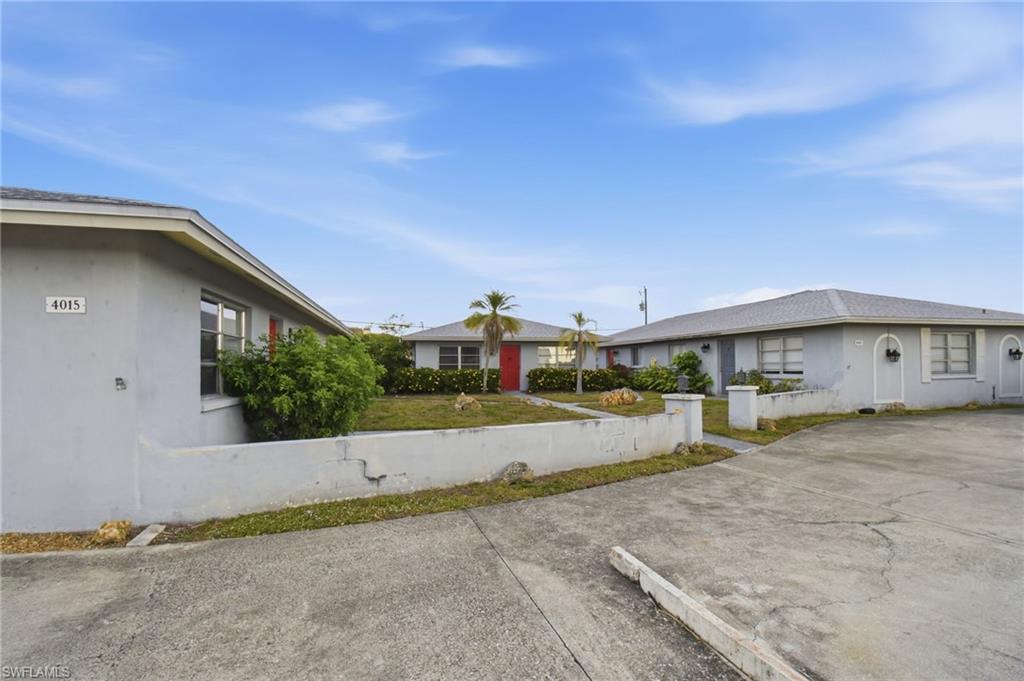 Exterior view of a multi-unit property with a paved driveway and pedestrian walkway