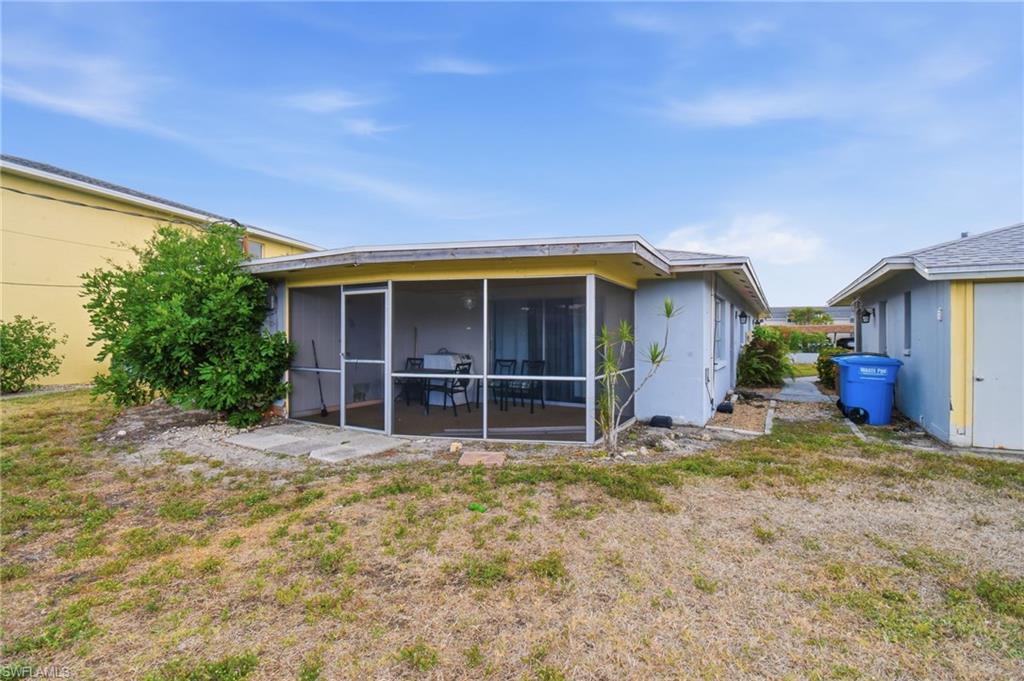 Rear exterior featuring a screened patio with concrete flooring, a light gray stucco finish, and a yellow soffit