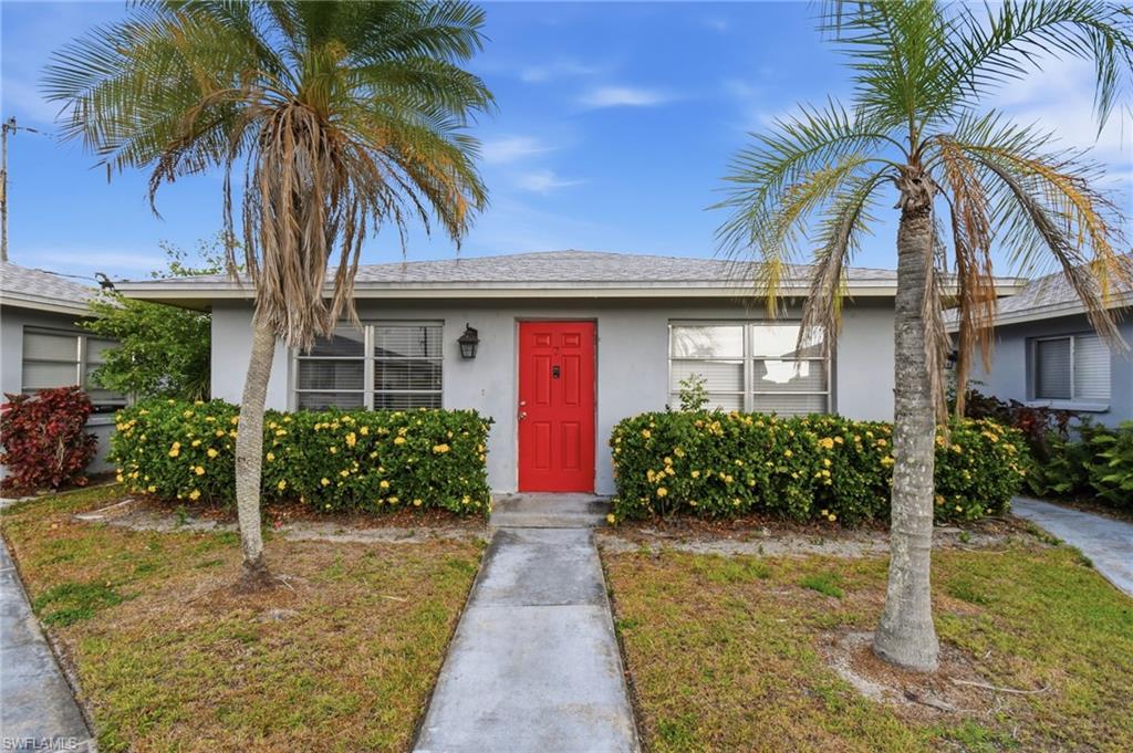 Light grey stucco exterior featuring a vibrant red entry door