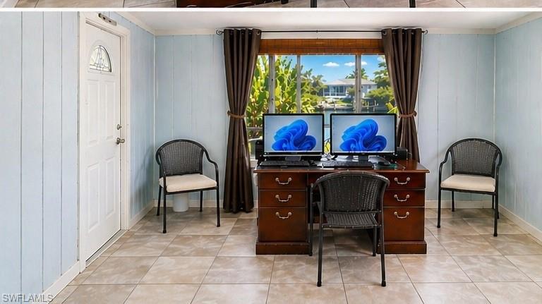 Interior space featuring a window with a water view, light blue paneled walls, and large format floor tiles