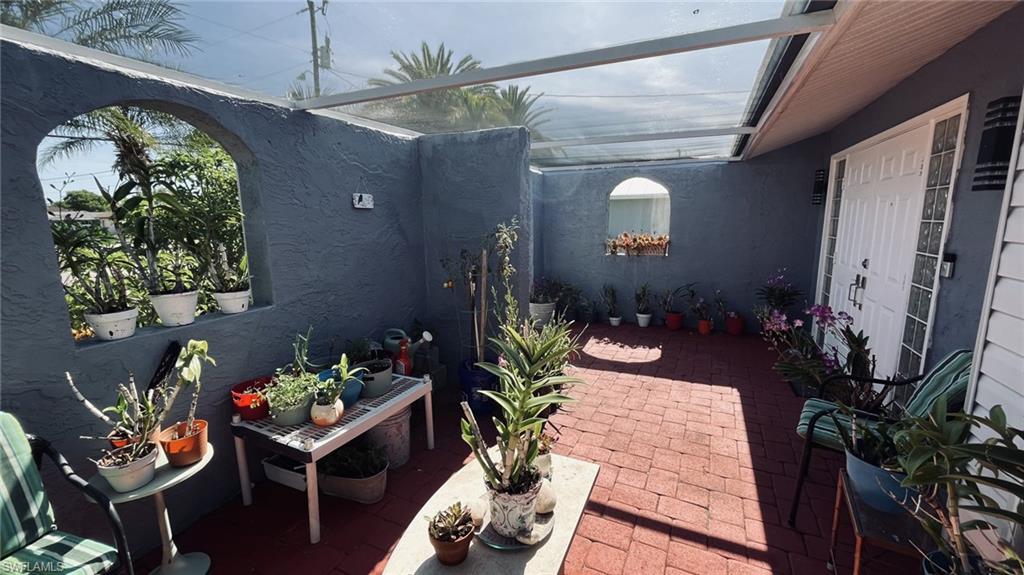Enclosed patio with red brick pavers, a clear panel roof, and arched wall openings