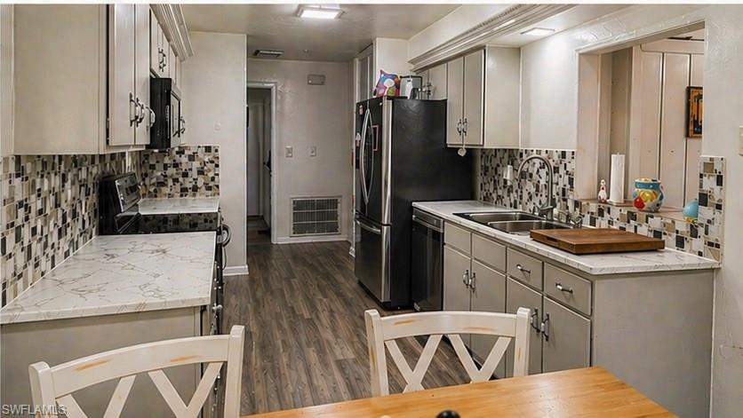 Kitchen featuring wood-finish flooring, light gray cabinetry, white marble-look countertops, a mosaic tile backsplash, and a double basin stainless steel sink