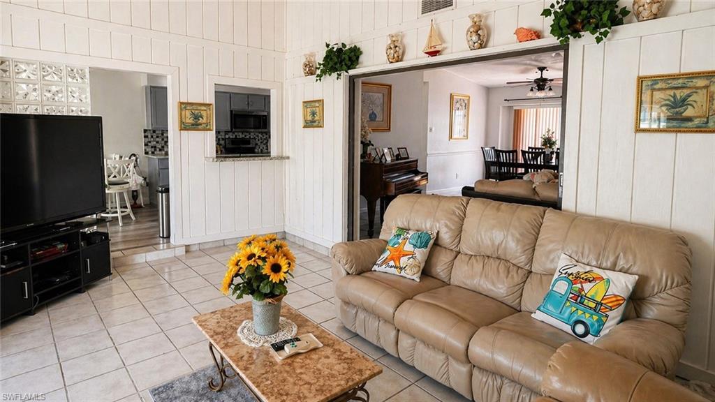 Spacious living area featuring white vertical paneling and light-toned tile flooring