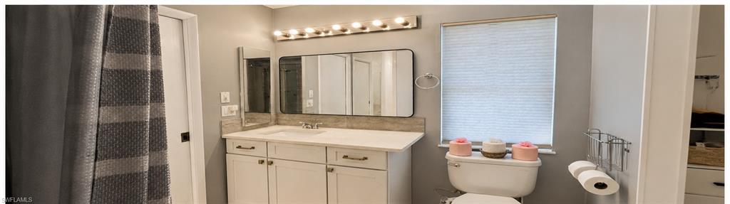 Bathroom vanity featuring a single basin, light-colored countertop, and white cabinetry with dark hardware
