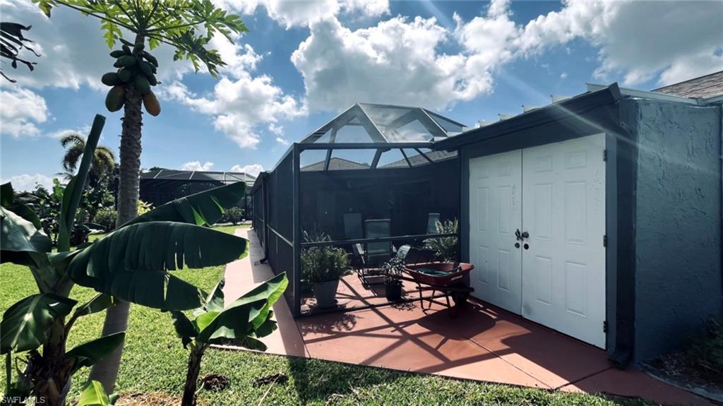 Screened outdoor patio with a textured concrete floor and an adjacent built-in storage shed featuring double white panel doors