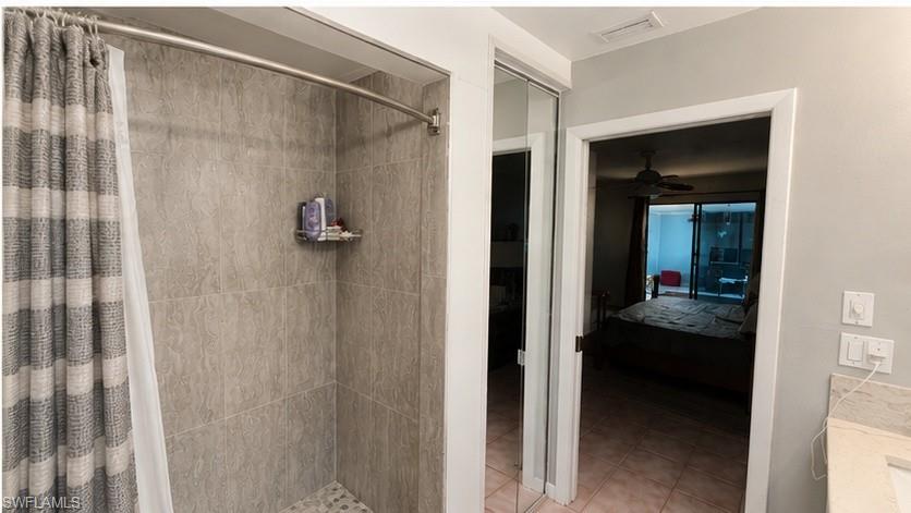 Shower with neutral-toned tiled walls, a curved shower rod, and a pebbled floor