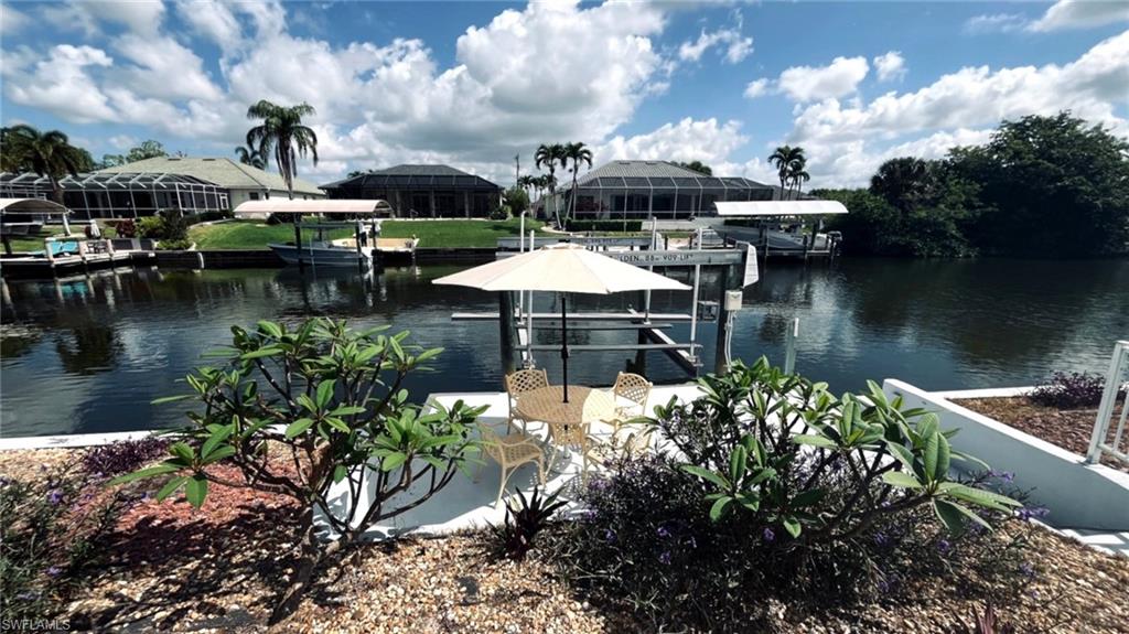 Waterfront property featuring a private boat lift, a dock, and mature landscaping