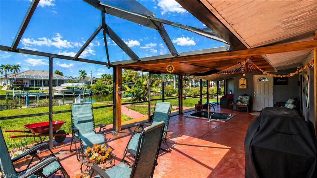 Screened lanai featuring a built-in hot tub, concrete flooring, and a ceiling with wood-finish beams