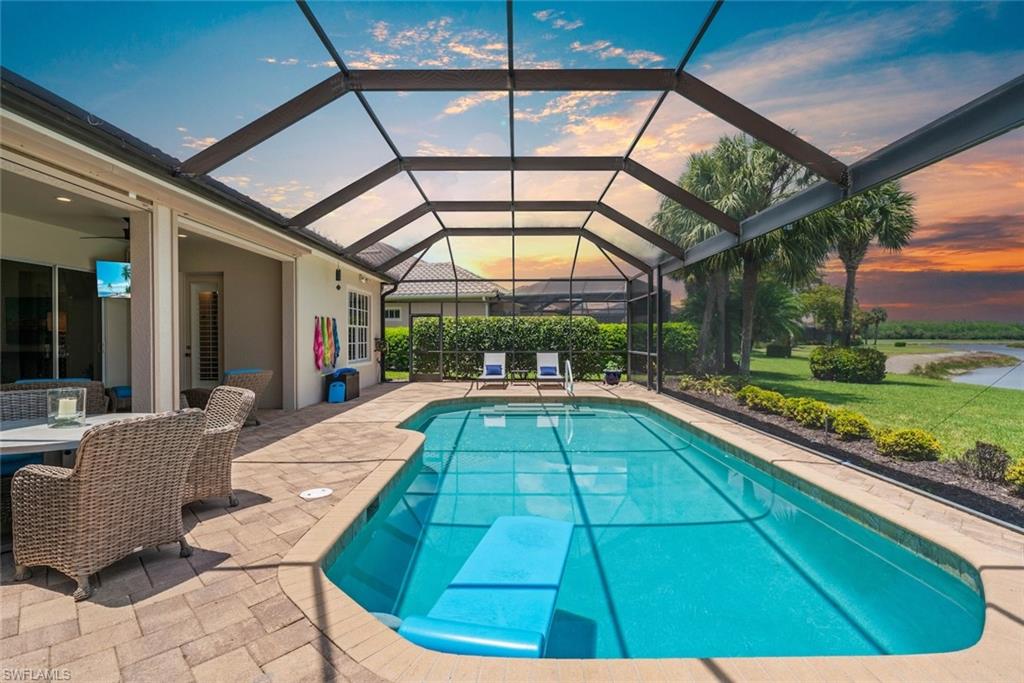 Screened-in pool and patio area featuring a paver deck, direct access to the interior, and landscaping and sunset
