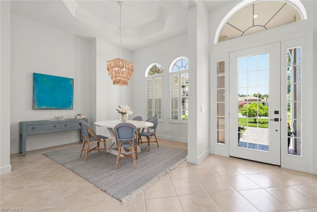 Dining area with tile floors, Serena & Lily chandelier and plantation shutters.
