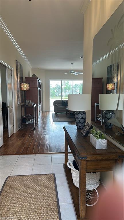Tiled living room with a ceiling fan and molding