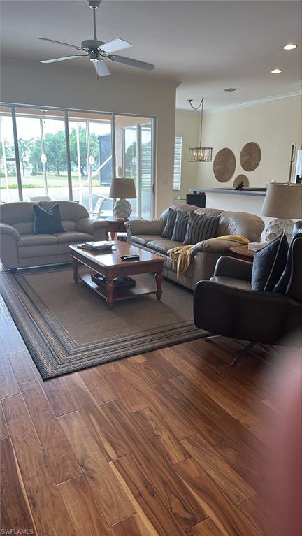 Living room with molding, ceiling fan, and wood finished floors