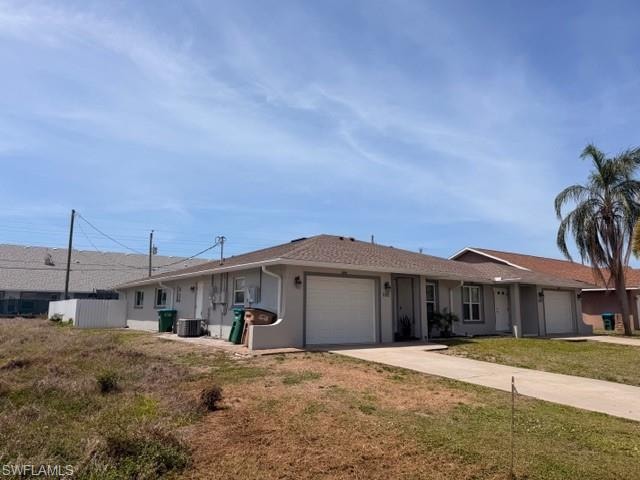 Well-maintained duplex with light gray stucco exterior, white garage doors, and separate driveways offering each unit full privacy