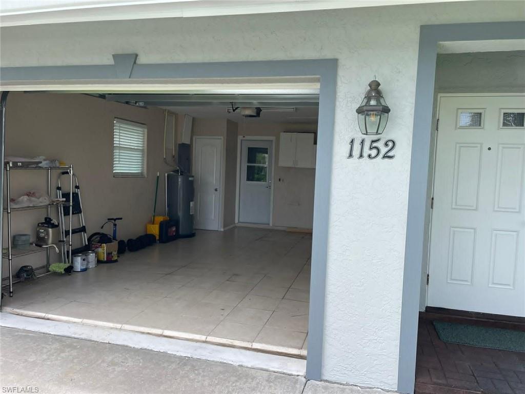 Attached garage with white paneled door, wall sconce lighting, and clearly marked unit numbers for tenant convenience