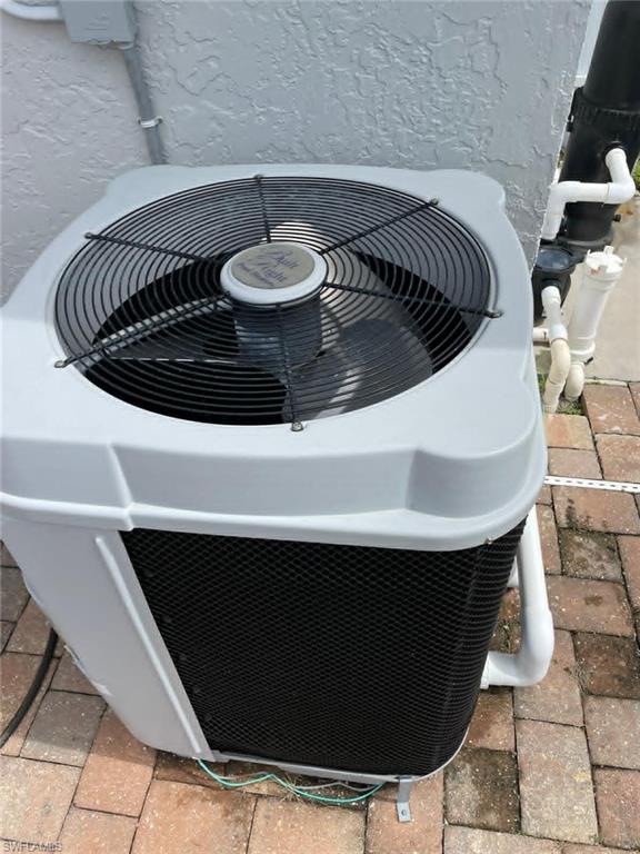 Exterior HVAC unit neatly placed on paver pad with PVC plumbing connections — well-maintained mechanical systems