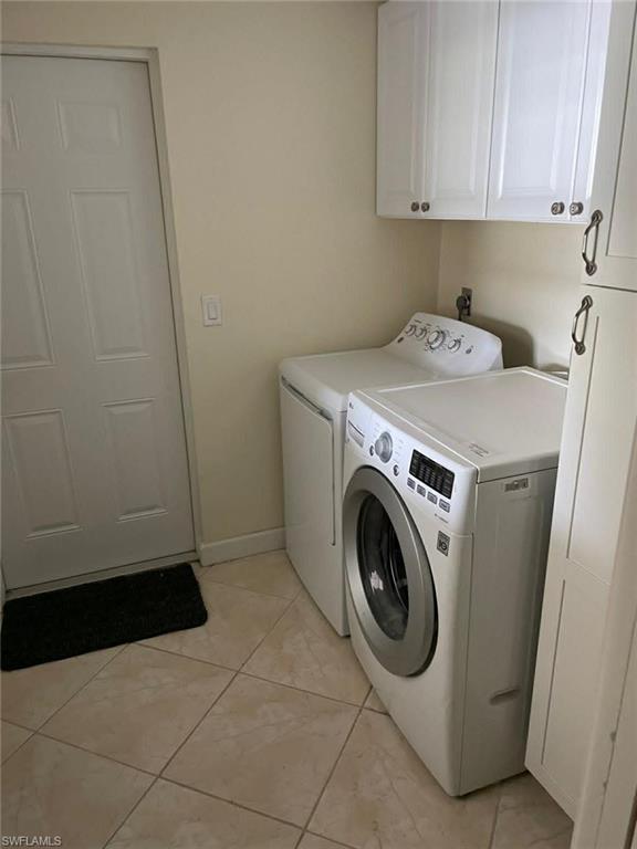 In-unit laundry area with white cabinetry, dark hardware pulls, and tile flooring — an excellent amenity that enhances rental appeal
