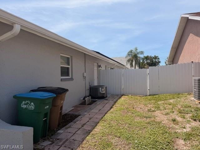 Fenced rear yard with paved walkway and stucco exterior — great outdoor space with privacy for tenants