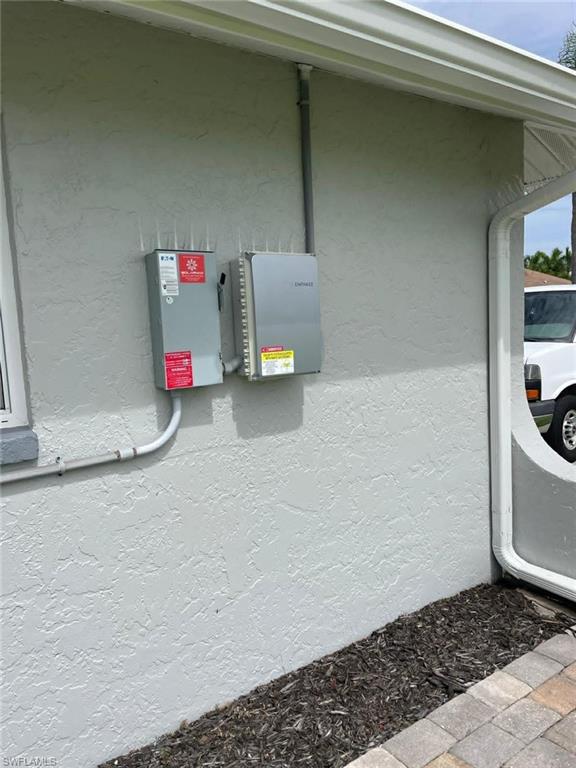 Exterior utility wall with electrical boxes and bird deterrent spikes — practical details showing a well-managed property