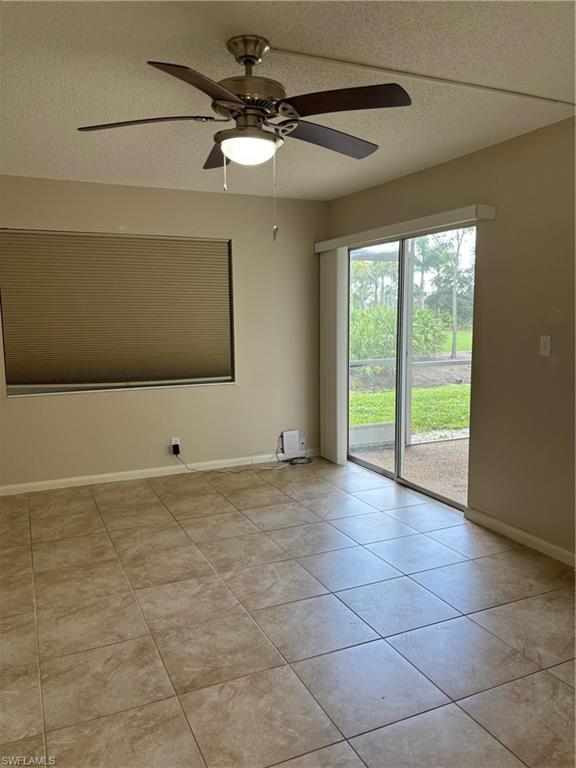 Tiled empty room featuring ceiling fan and a textured ceiling